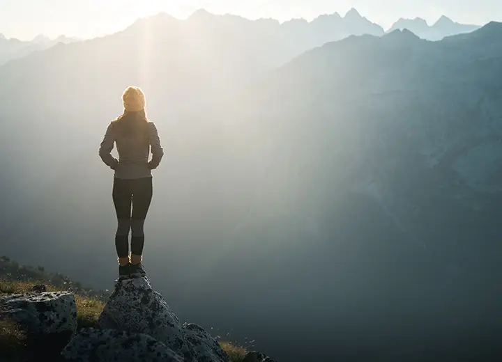 Female standing on rock looking over mountains