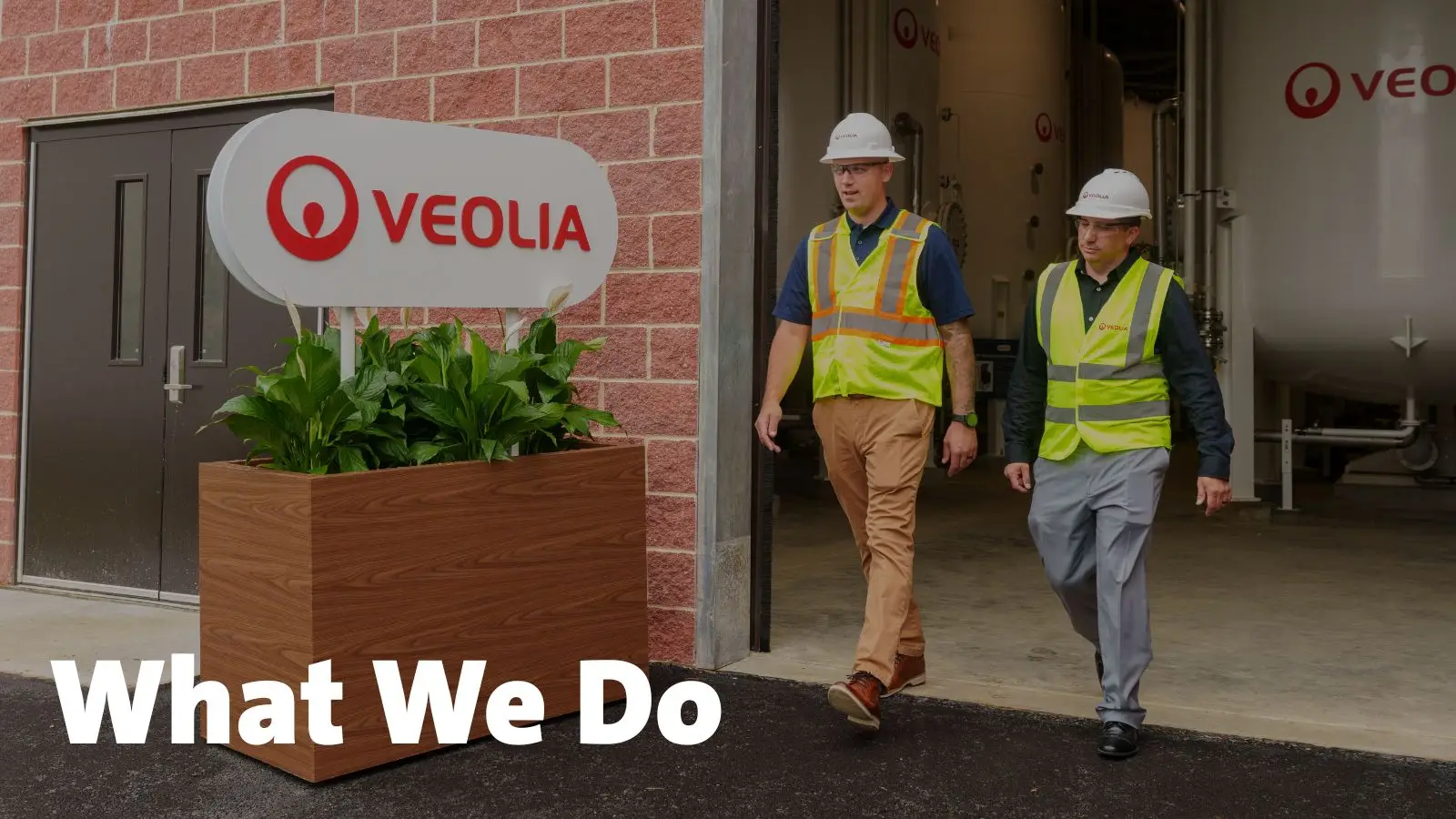 Two workers with What We Do verbiage