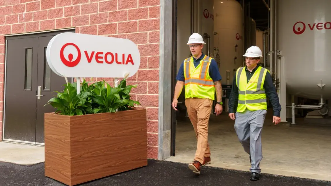 Two Veolia employees walking out of a facility by a Veolia sign